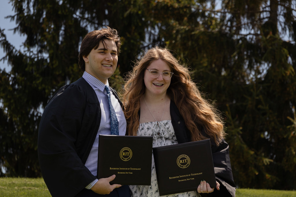 Two college graduates holding diplomas