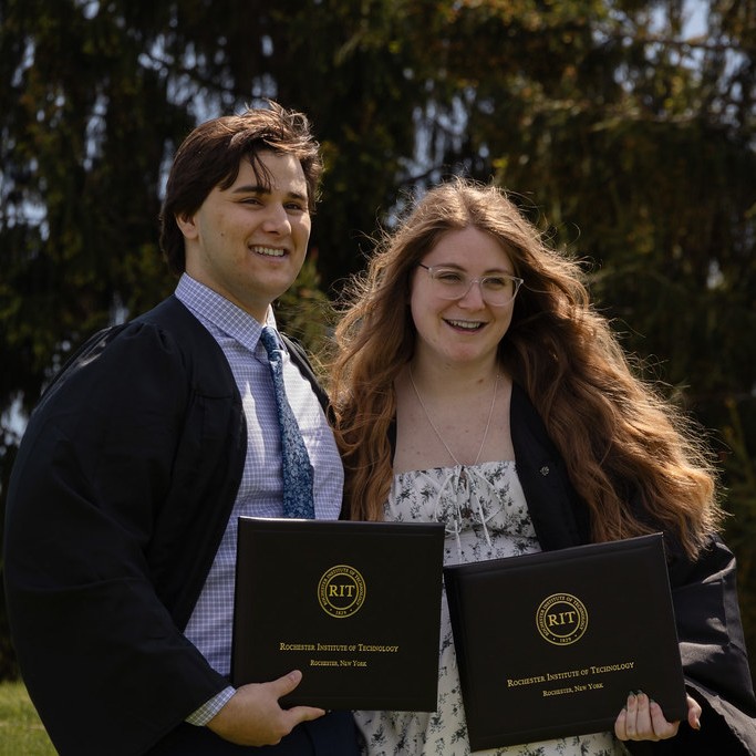 Two college graduates holding diplomas
