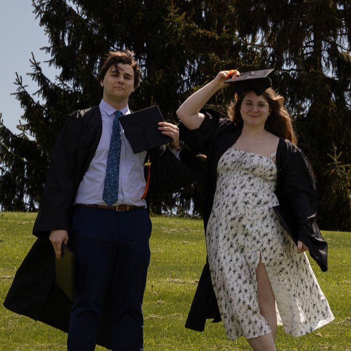 Two college graduates holding caps