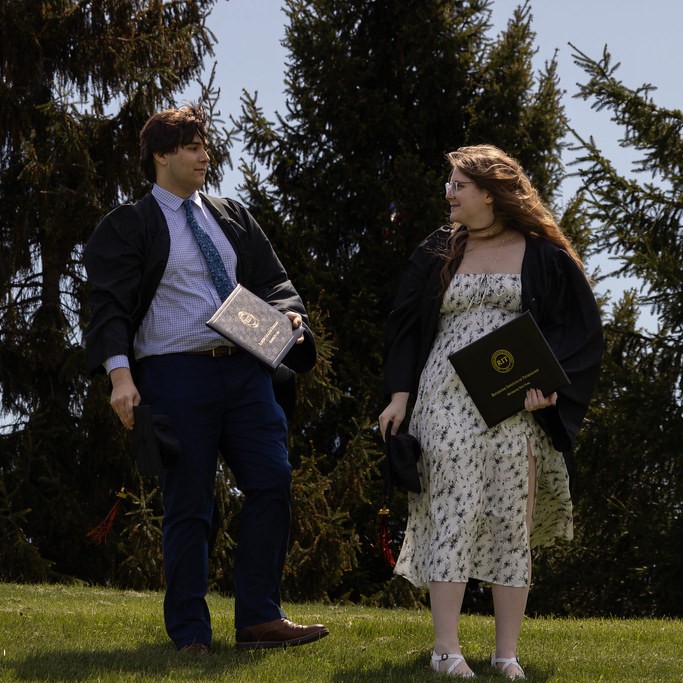 Two college graduates holding diplomas